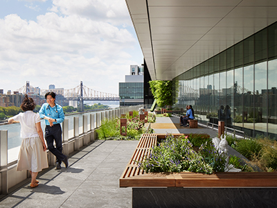 Two people lean against a railing overlooking the Hudson River in a rendering of a terrace at the David H. Koch Center for Cancer Care.