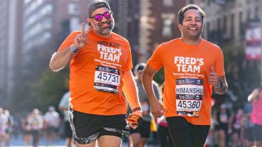 Two runners wearing Fred’s Team shirts, jogging and smiling. 