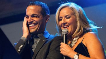 Dr. Rebecca Timlin-Scalera and Tom Scalera stand together, she speaks into a microphone as he laughs. 