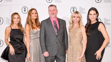 A group of four women and one man, dressed in chic eveningwear, smile in front of a step and repeat that reads The Society of MSK. 