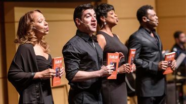 A group of men and women performing, holding books that read “Visible Ink.” 