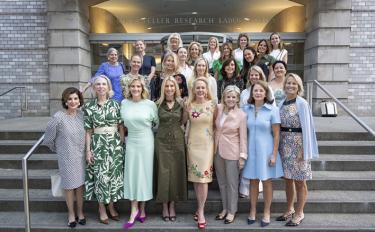 Twenty-five members of The Society of the MSK stand in rows on the steps of MSK’s Rockefeller Research Laboratories. 