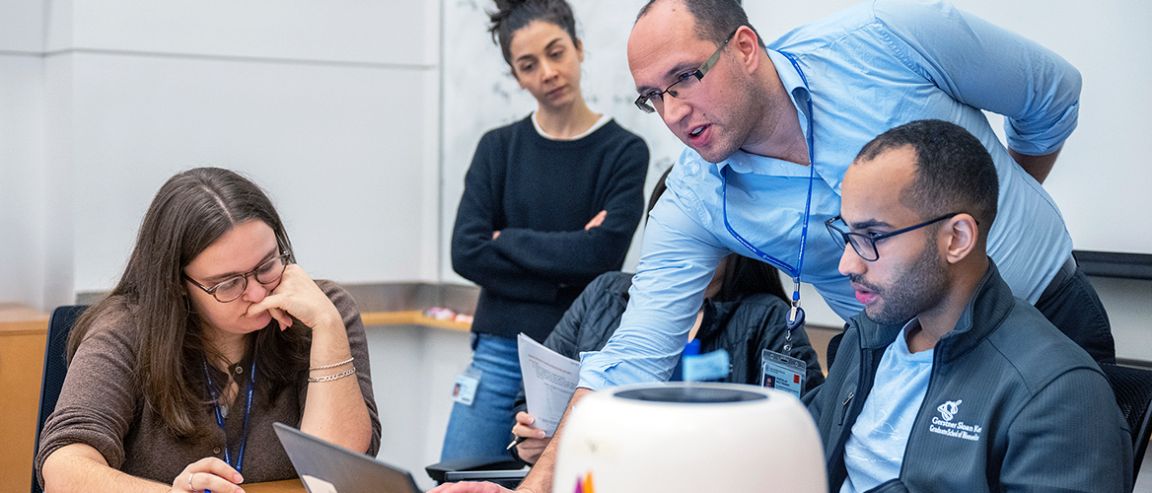 Five people in a classroom at MSK’s Gerstner Sloan Kettering Graduate School of Biomedical Sciences.