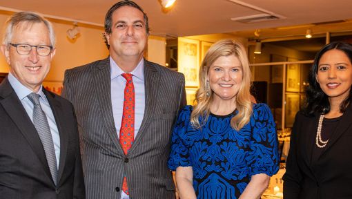 Four people in formal attire smiling at an indoor event.