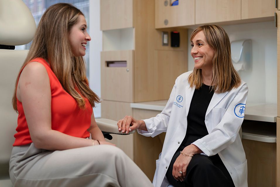 MSK’s Andrea Cercek, MD, sits and speaks with a patient in an MSK care room.  