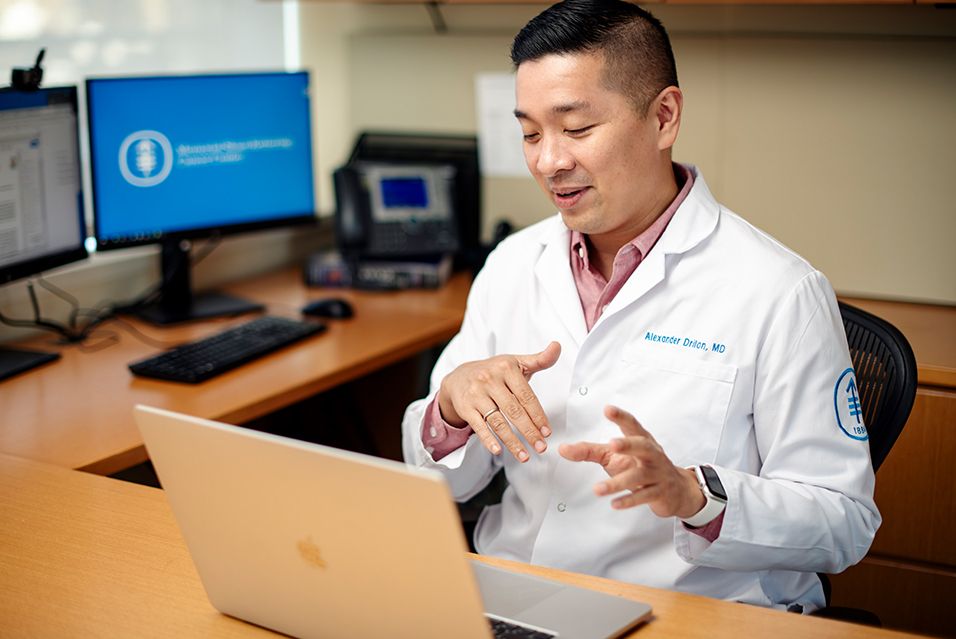 Dr. Alexander Drilon, a thoracic oncologist and Chief of the Early Drug Development Service at MSK, seated at a desk with a laptop computer open in front of him. 