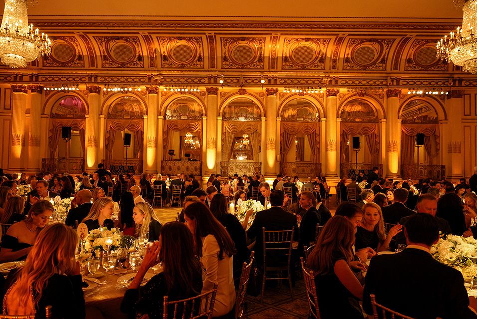 A photograph displaying the dimly lit, elegant ballroom of the Plaza Hotel on event night. 