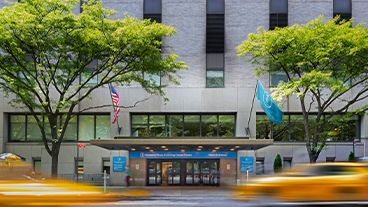 Street view of the MSK entrance with blurred yellow cabs passing by.